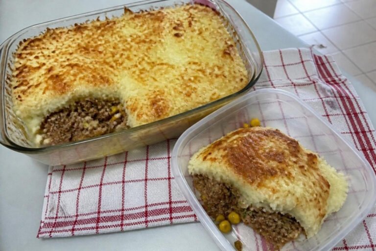 Escondidinho de carne moída com purê de batata e queijo gratinado no refratário e numa marmita ao lado