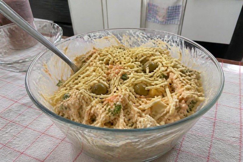 Tigela de vidro com salpicão de frango cremoso, com cenoura, azeitona, salsinha e batata palha por cima